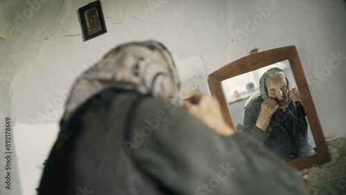 Elderly lady adjusting her kerchief in a mirror photo