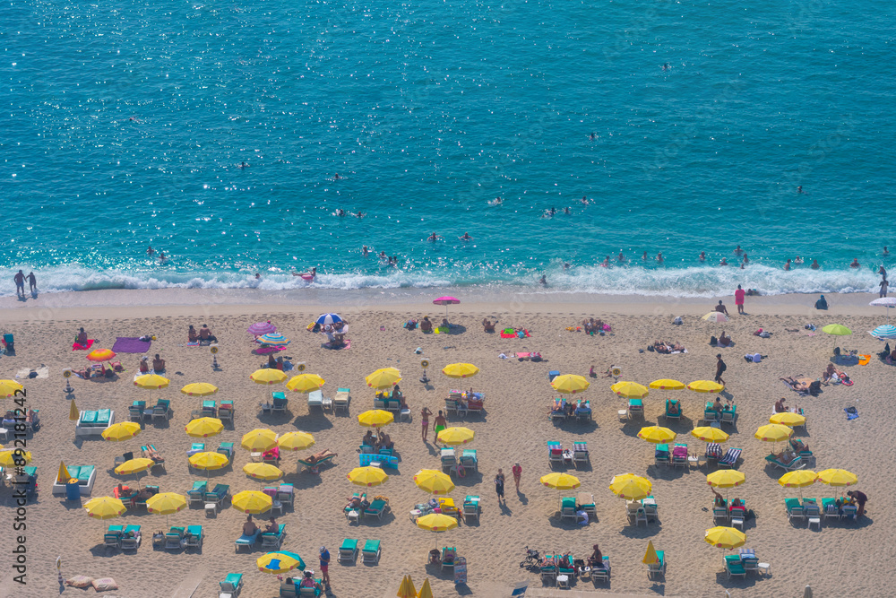 Beautiful top view of blue sea ocean water and beach shore with lots many of people tourists on lounge chairs,sun loungers in summertime and bright sunlight sun.Tourism destination,vacation,holiday Beautiful top view of blue sea ocean water and beach shore with lots many of people tourists on lounge chairs,sun loungers in summertime and bright sunlight sun.Tourism destination,vacation,holiday