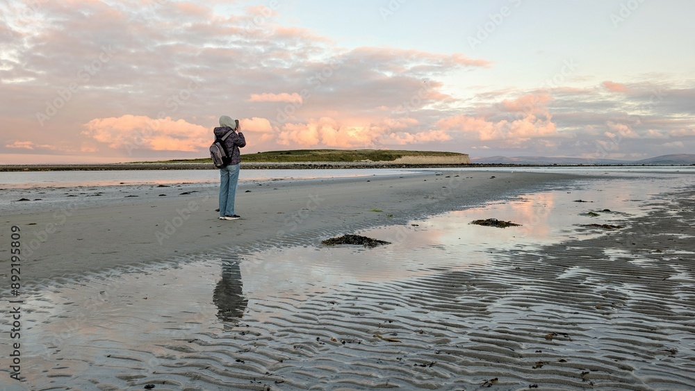 woman hiker backpacker enjoying coastal sunset scenery at sandy Silverstrand beach, Galway, Ireland, adventure and lifestyle concept, people in nature background