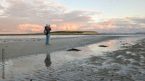 Obraz na płótnie woman hiker backpacker enjoying coastal sunset scenery at sandy Silverstrand beach, Galway, Ireland, adventure and lifestyle concept, people in nature background w salonie