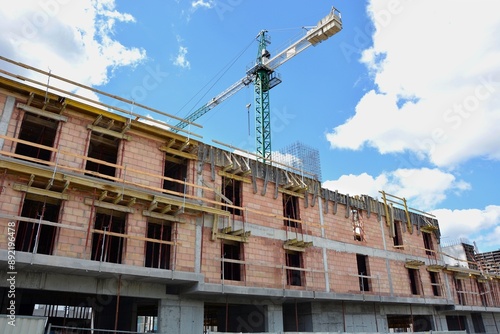 Building with concrete and red bricks under construction and crane © Gold Picture