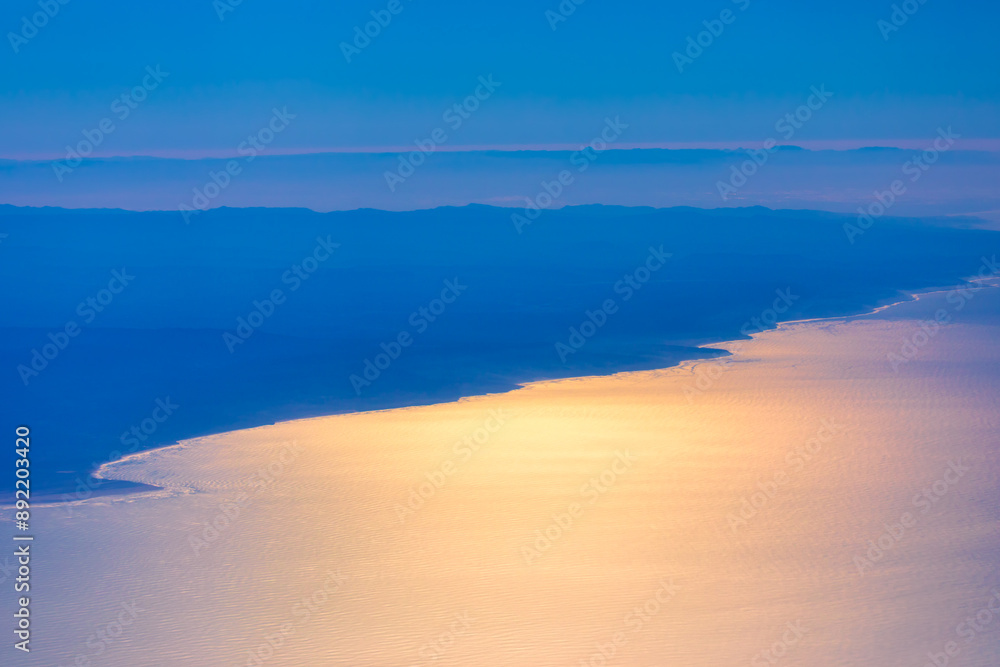 Fototapeta premium Flight over Atlantic Ocean and Morocco coast. Aerial view of ocean waves meeting majestic mountains in a scenic landscape