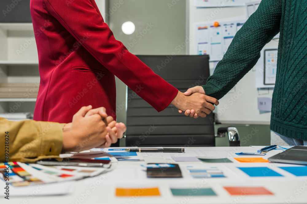 © M+Isolation+Photo - A group of people collaborates around a desk, discussing and reviewing user interface (UI) and user experience (UX) elements. usability, accessibility, and design principles for product development.