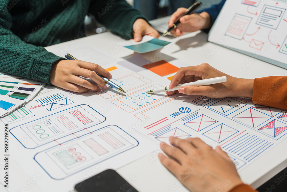 A group of people collaborates around a desk, discussing and reviewing user interface (UI) and user experience (UX) elements. usability, accessibility, and design principles for product development. A group of people collaborates around a desk, discussing and reviewing user interface (UI) and user experience (UX) elements. usability, accessibility, and design principles for product development.
