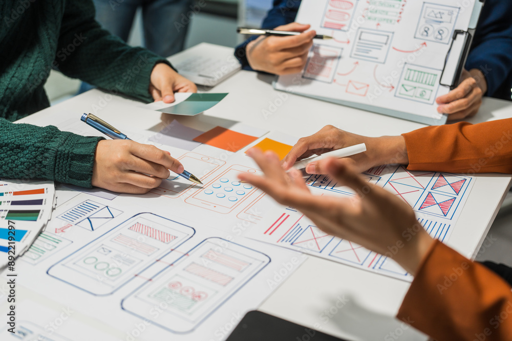 Φωτογραφία A group of people collaborates around a desk, discussing and reviewing user interface (UI) and user experience (UX) elements