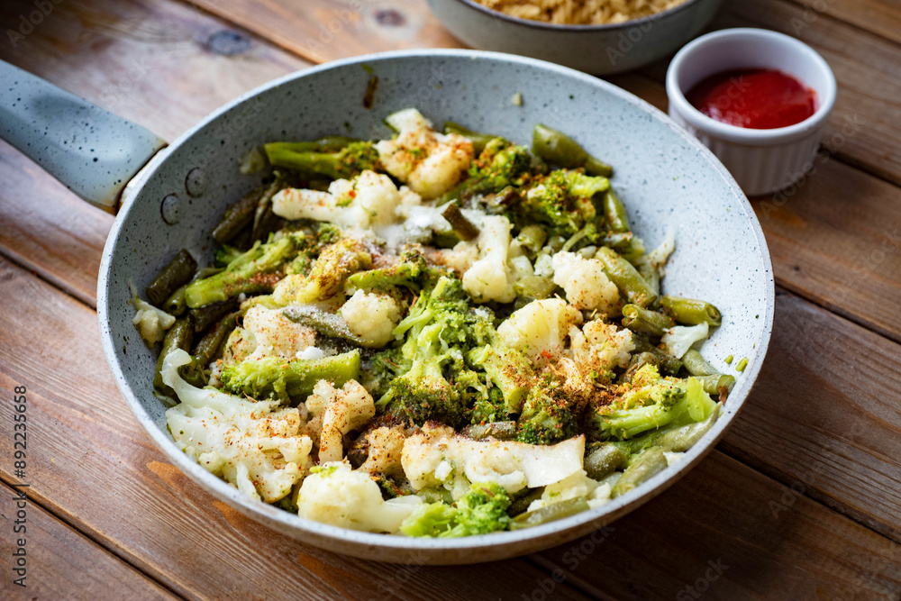 Vegetables in a pan with spices. Cauliflower, broccoli and green beans in a pan with spices. Vegetarian lunch. Close-up Vegetables in a pan with spices. Cauliflower, broccoli and green beans in a pan with spices. Vegetarian lunch. Close-up