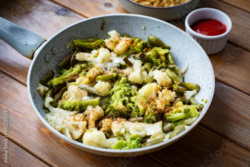 Vegetables in a pan with spices. Cauliflower, broccoli and green beans in a pan with spices. Vegetarian lunch. Close-up