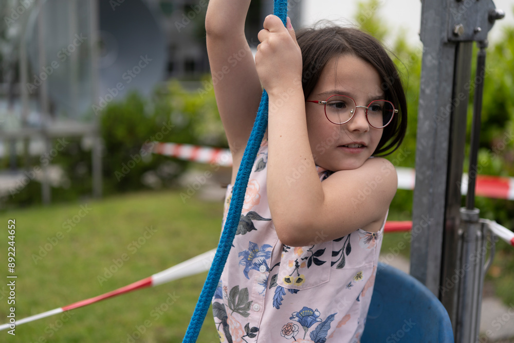A little girl pulls a rope trying to lift herself in a chair. Concept of experimental children's education. A little girl pulls a rope trying to lift herself in a chair. Concept of experimental children's education.