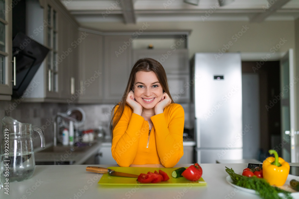 Young woman standing at the table in the kitchen. fresh fruits and vegetables on the table. Young woman standing at the table in the kitchen. fresh fruits and vegetables on the table.