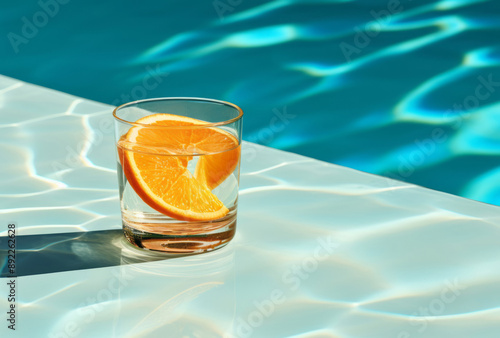 A glass of water sits next to a slice of mango, its kitsch aesthetic, poolcore, bold and dynamic lines, serenity, and calm apparent in orange and aquamarine. photo