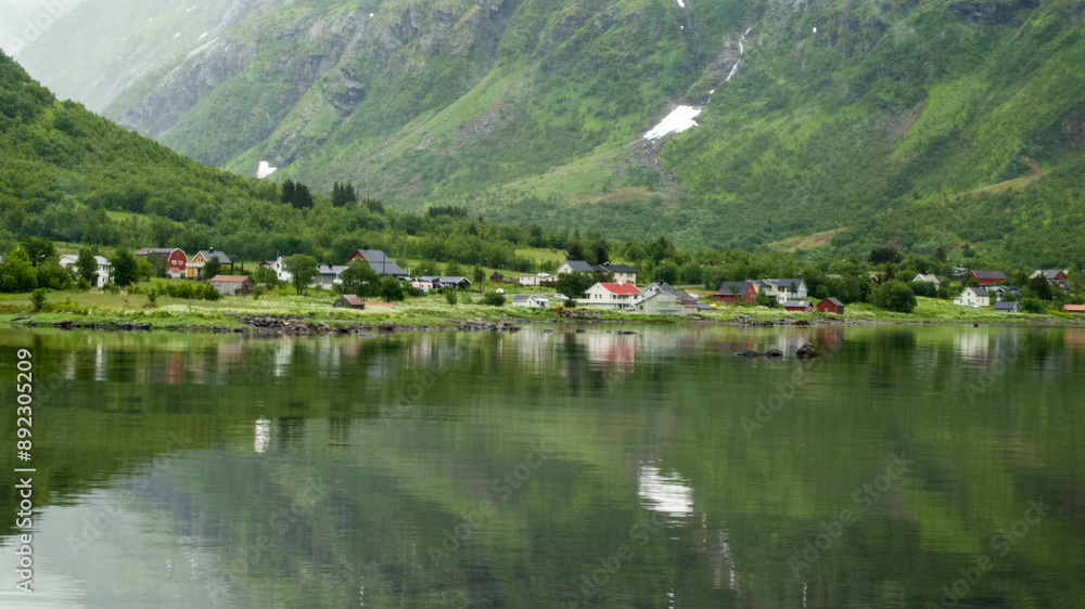 Fototapeta premium Traditional Scandinavia houses next to the fjord with greenery mountain reflection from the fjord water
