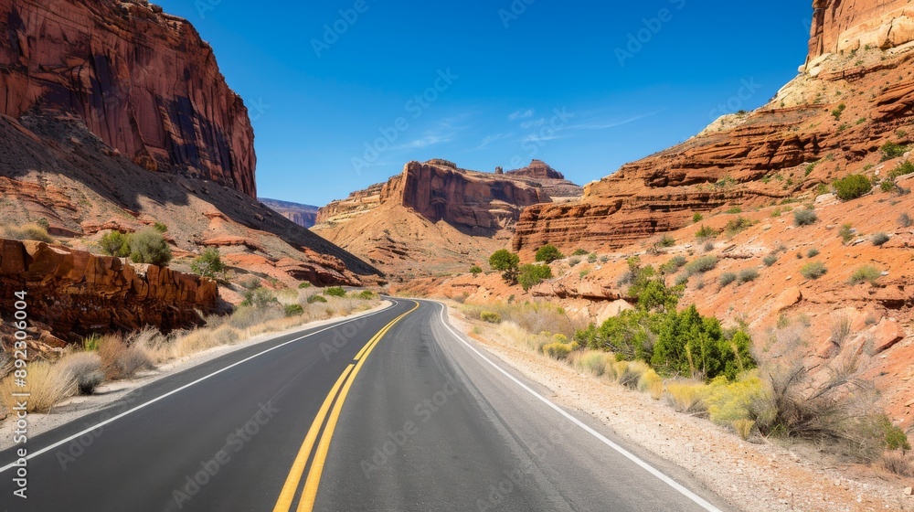 Scenic desert highway winding through red rock canyon on a sunny day, with clear blue sky and rugged landscape. Scenic desert highway winding through red rock canyon on a sunny day, with clear blue sky and rugged landscape.