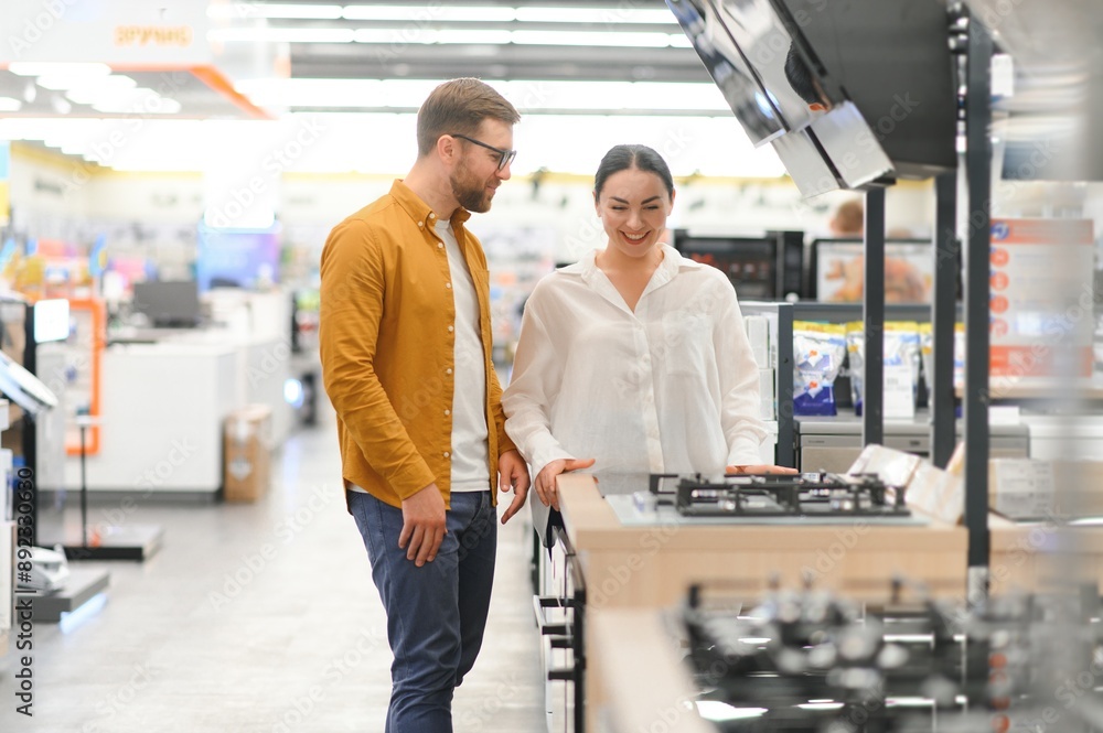 Young man and woman buying new gas stove in appliances shop Young man and woman buying new gas stove in appliances shop
