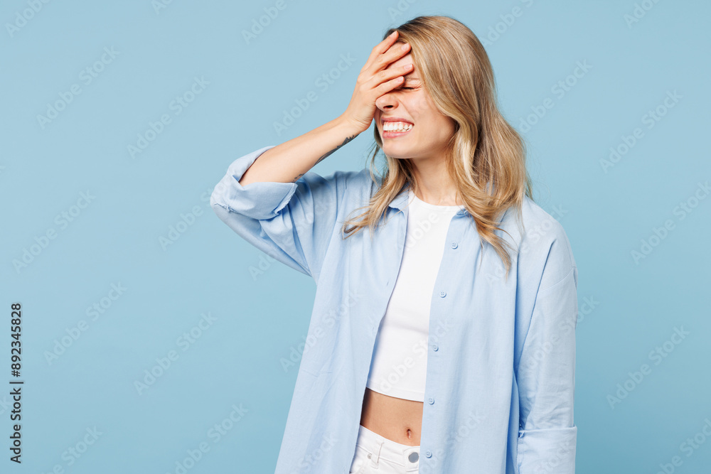 Young smiling happy woman wears white top shirt casual clothes put hand on face facepalm epic fail mistaken omg gesture isolated on plain pastel light blue cyan background studio. Lifestyle concept. Young smiling happy woman wears white top shirt casual clothes put hand on face facepalm epic fail mistaken omg gesture isolated on plain pastel light blue cyan background studio. Lifestyle concept.