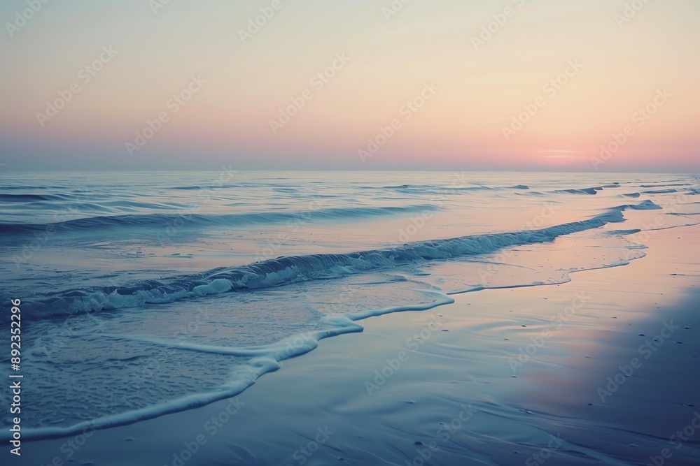 Soft waves lap the shore at sunset, creating a peaceful and serene scene.  The sky is a blend of pink and orange, reflecting on the water.