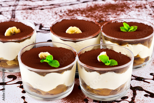 Dessert with tiramisu and chocolate and sweetness. Cake coffee recipe concept. A glass ated with a tiramisu and mint. A dessert ated with chocolate, mint, and lifestyle a tiramisu. photo