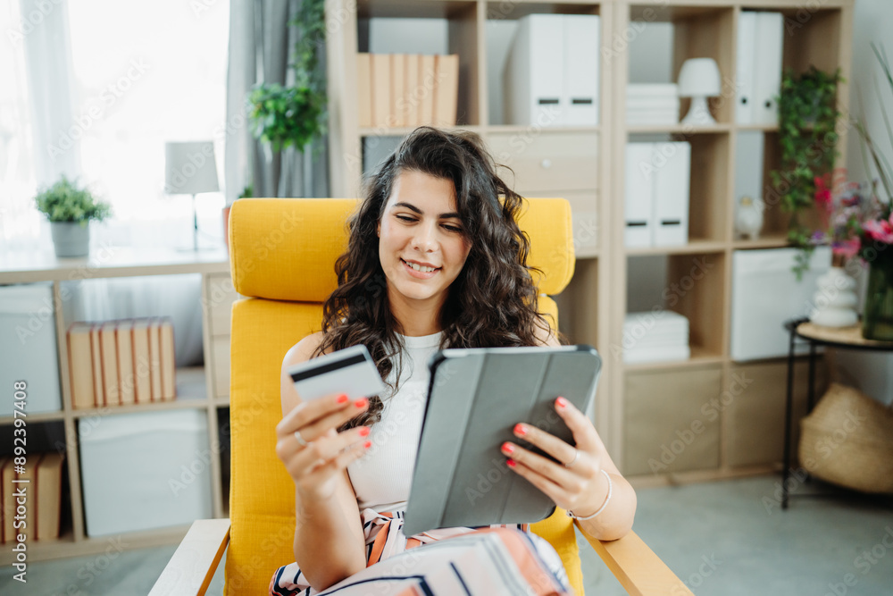 One young beautiful caucasian woman is buying online on her tablet using credit card from her home One young beautiful caucasian woman is buying online on her tablet using credit card from her home