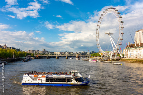 London Eye (Millenium Wheel) and cruise boat on Thames river, UK photo