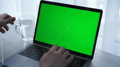 A man's hand with a glass of water.
An IT specialist works in a snow-white office behind the screen of a laptop.
Green gadget screen.
Chromekey, office worker concept, modern technology photo