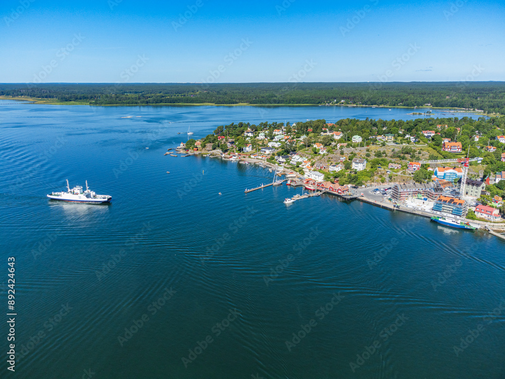 Car ferry approaching the dock, swedish archipelago, summer, blue sky and blue sea. Dalarö island with houses and its coastline Car ferry approaching the dock, swedish archipelago, summer, blue sky and blue sea. Dalarö island with houses and its coastline
