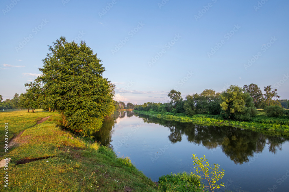 A peaceful river flows through a verdant landscape, reflecting the lush trees and tranquil sky on its surface. The morning light casts a soft glow over the scene, creating a sense of serenity. A peaceful river flows through a verdant landscape, reflecting the lush trees and tranquil sky on its surface. The morning light casts a soft glow over the scene, creating a sense of serenity.