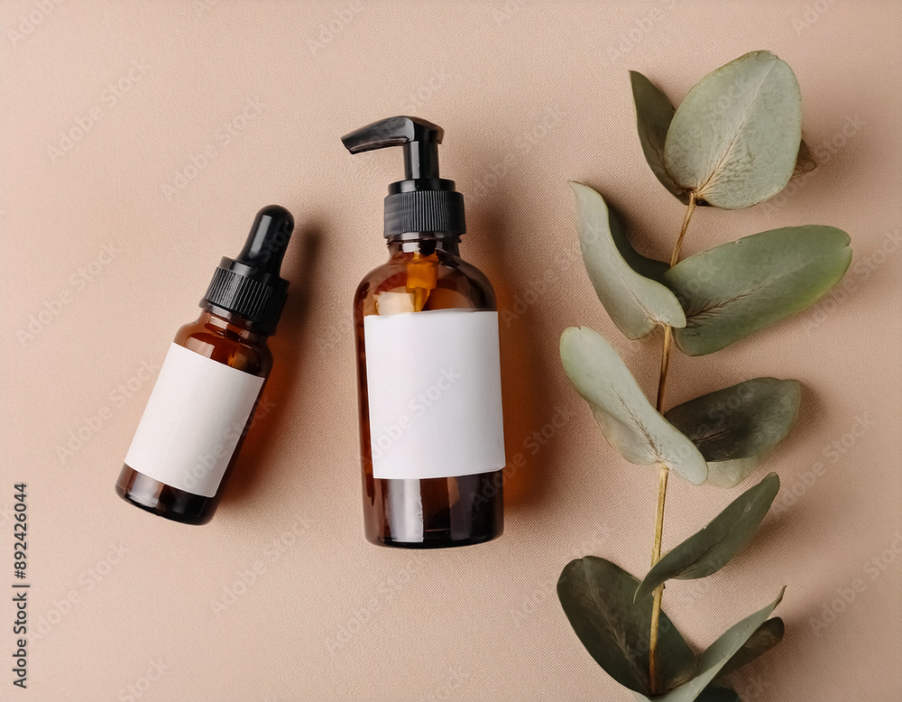 Elegant Amber Glass Cosmetic Bottles with Blank Labels and Eucalyptus Leaf on Beige Background Elegant Amber Glass Cosmetic Bottles with Blank Labels and Eucalyptus Leaf on Beige Background