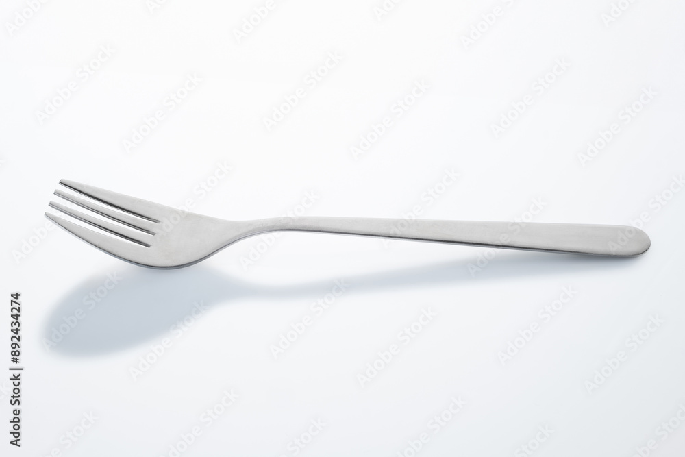 Une fourchette sur fond blanc avec une ombre de cuillère en trompe l'œil Une fourchette sur fond blanc avec une ombre de cuillère en trompe l'œil