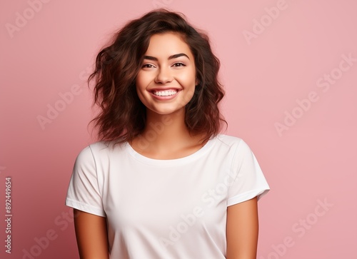 Portrait of a smiling beautiful woman in a white t-shirt looking away over a pink background with copy space, side view