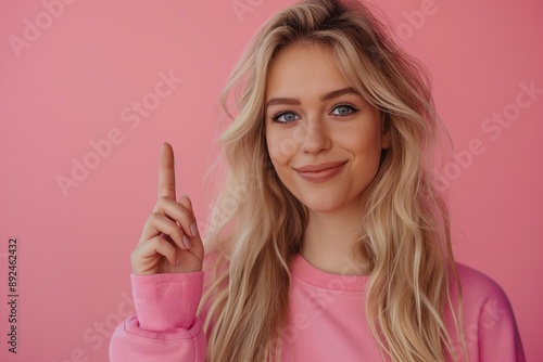 Portrait of beautiful blonde woman with long hair, wearing pink casual and smiling