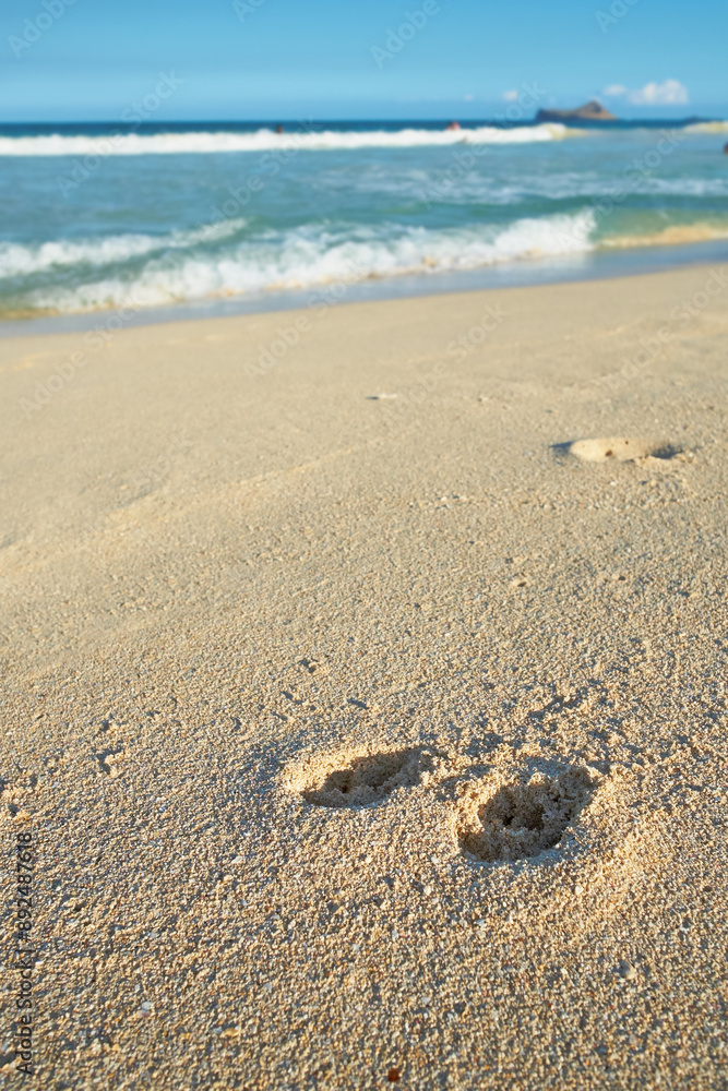 Nature, ocean and footprints in sand for travel, vacation or holiday in summer by coastal island. Walk mark, steps and sea waves on LaniKai beach for tropical weekend trip at destination in Hawaii. Nature, ocean and footprints in sand for travel, vacation or holiday in summer by coastal island. Walk mark, steps and sea waves on LaniKai beach for tropical weekend trip at destination in Hawaii.