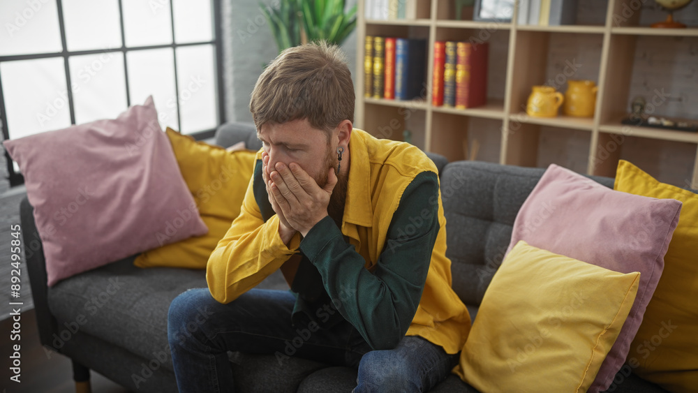 Distressed man sitting indoors holding face in hands, showcasing emotions, mental health, and solitude. Distressed man sitting indoors holding face in hands, showcasing emotions, mental health, and solitude.
