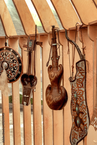 Traditional Kazakh leather flask for drinks, a quiver with a bow and arrows, a musical instrument - kobyz and a warrior's shield on the wall of a street store photo