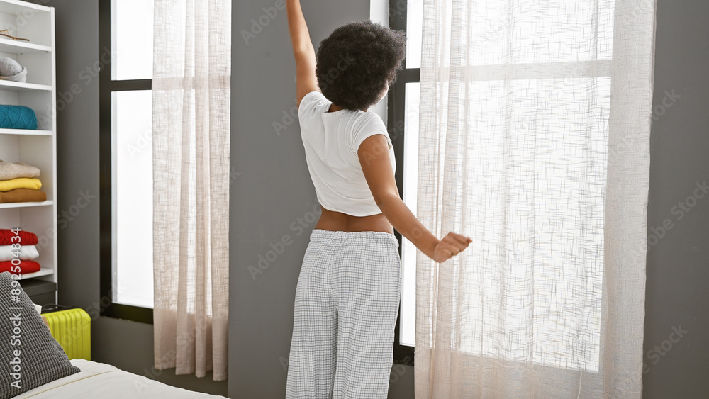 African american woman stretching in a modern bedroom with white curtains and comfortable home decor African american woman stretching in a modern bedroom with white curtains and comfortable home decor