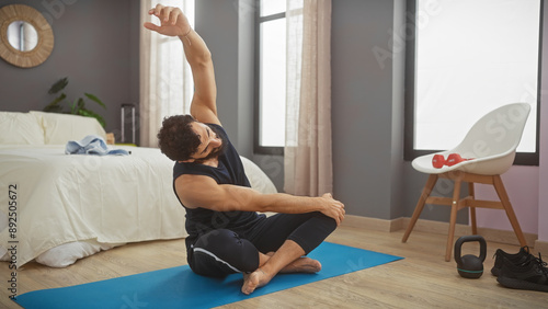 Man stretching on a yoga mat in a modern bedroom interior, promoting wellness and an active lifestyle at home.