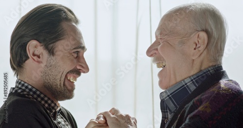 Fotografía Middle-aged man and his father talking and then embracing in relief smiling, laughing and holding hands