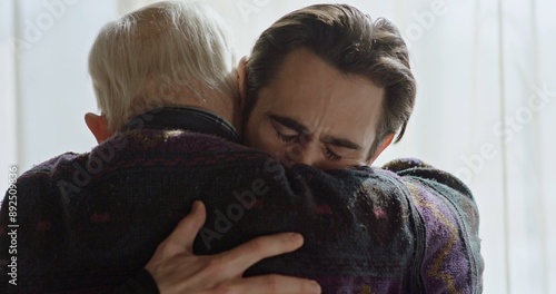 The last farewell to an adult son with an old father near the window. Strong emotional scene.