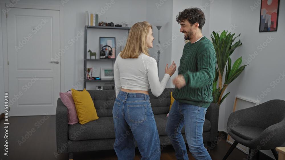 Obraz premium A joyful man and woman dance together in a cozy living room, expressing happiness and affection in their home interior.