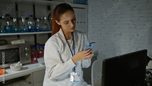 Wallpaper Mural A focused caucasian woman scientist in a lab coat using a smartphone in a modern laboratory setting Torontodigital.ca