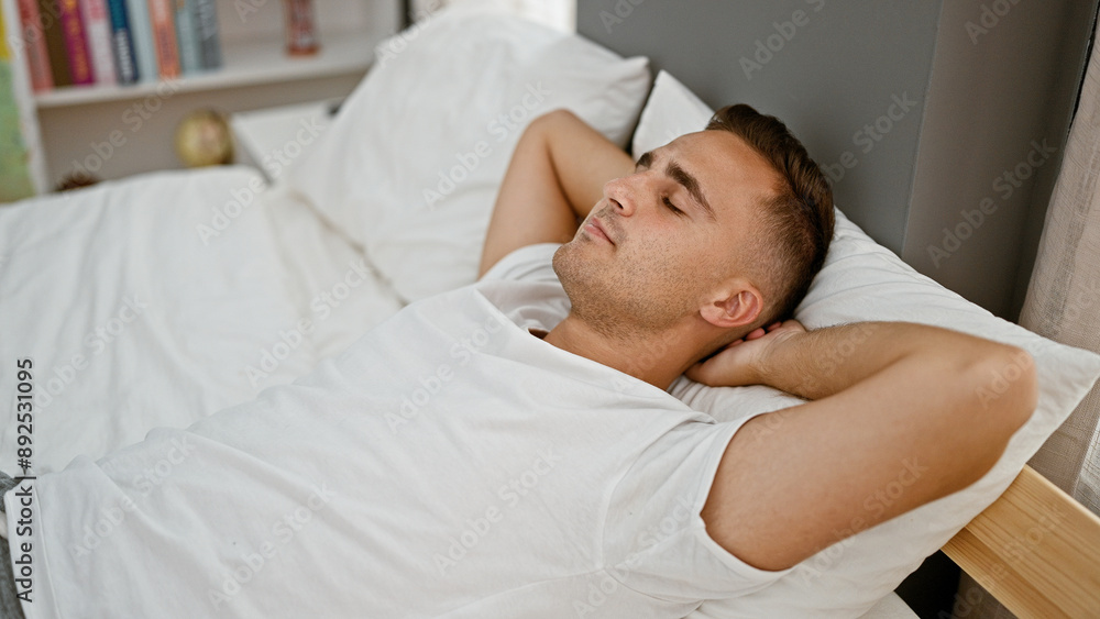 A young man relaxing in bed with eyes closed in a peaceful bedroom setting. A young man relaxing in bed with eyes closed in a peaceful bedroom setting.