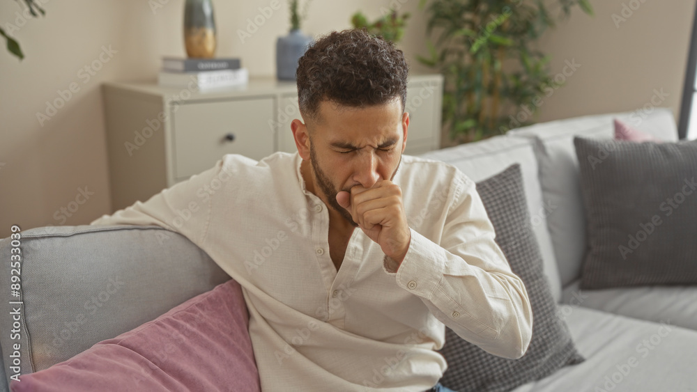 Young hispanic man coughing at home on a couch in the living room. Young hispanic man coughing at home on a couch in the living room.