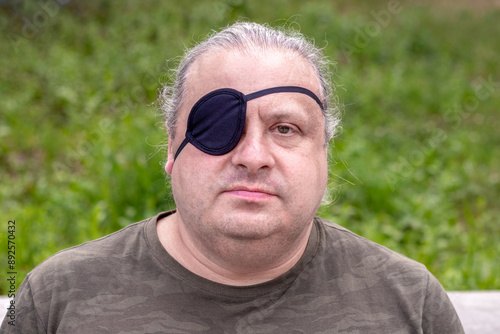 Close-up portrait of a blind, visually impaired man with a black medical patch on his eye
