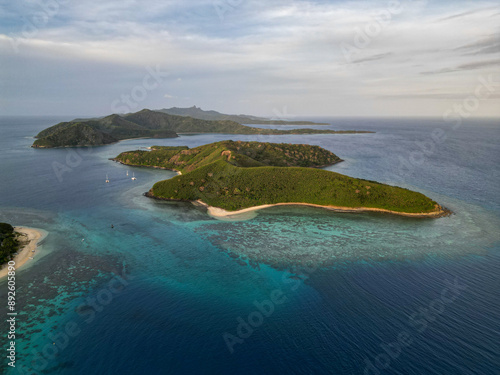 Aerial view of tropical islands in Fiji at sunset. Calm, shallow turquoise waters and coral reef surround the remote beaches in the tourist destination of the Yasawa islands. 