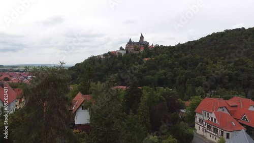 Aerial drone view of the tourist town Wernigerode in Lower Saxony, Germany. A nature landscape with forest or woods surrounding the castle, residential, vacation homes, apartment buildings and hotels.