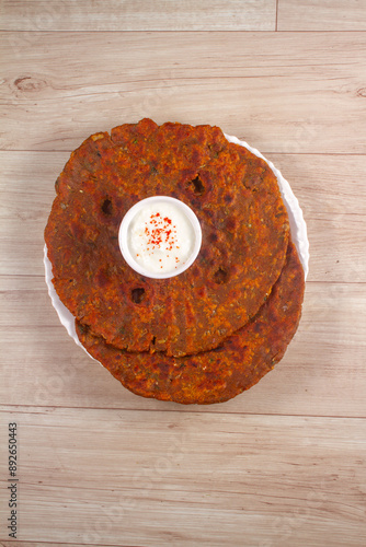 Thalipith or Thalipeeth Maharashtrian popular nutritious breakfast, isolated over a rustic wooden background, selective focus