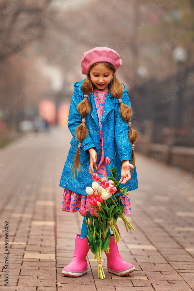 Beautiful girl kid with spring pink tulips flowers bouquet at city street. Beautiful girl kid with spring pink tulips flowers bouquet at city street.