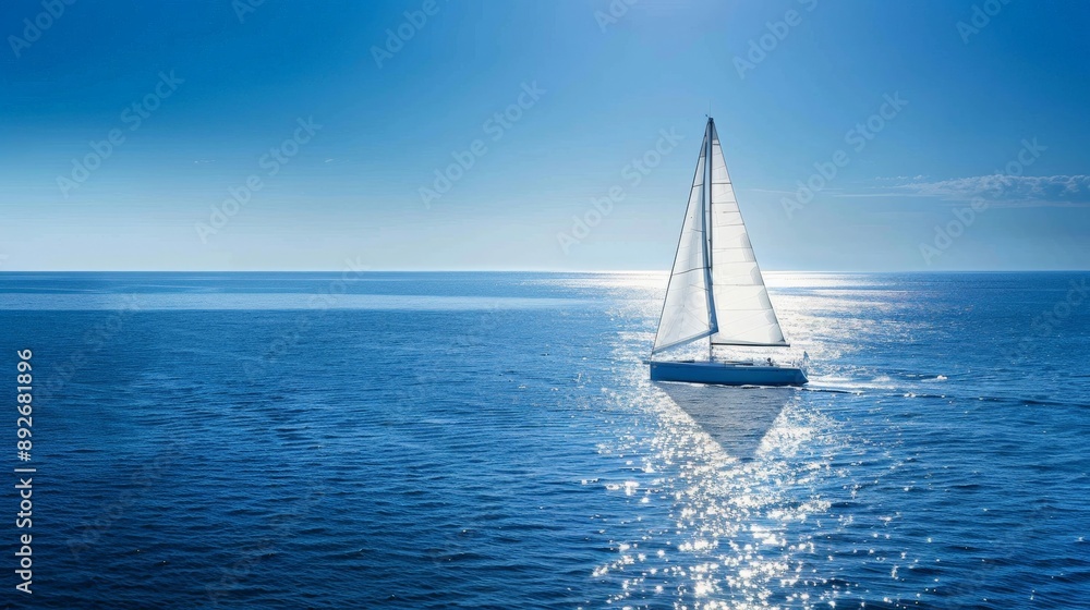 Obraz premium Sailboat gliding across a calm blue sea under a clear sky