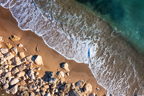 Aerial drone overhead view of beautiful wave splash on a rocky coastline photo