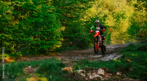 Professional enduro bike rider on action, dirt ride on the muddy road. Motocross sport. 