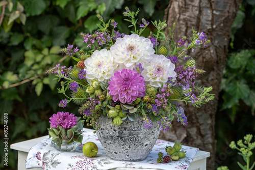 Blumen-Arrangement mit Dahlien, Wiesen-Salbei, Wiesenwicke, Distel, Haselnüssen und Brombeeren im vintage Blumentopf im Garten photo