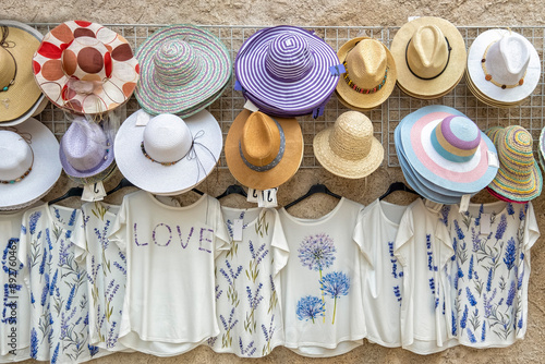 detail of a street market stall with colourful straw and cloth hats and pamelas and floral patterned tee shirts with lavender designs photo